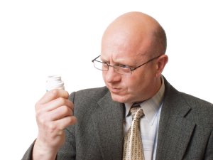 bald man looking at pill bottle