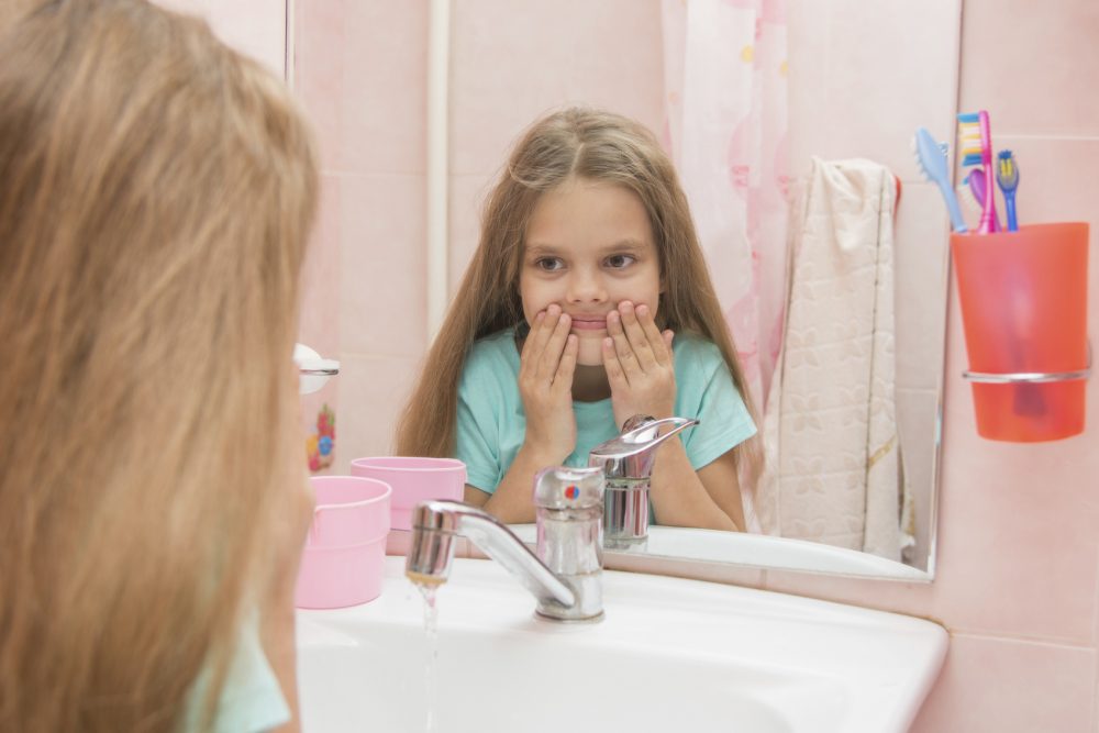 Six year old girl washes her mouth after using mouthrinse
