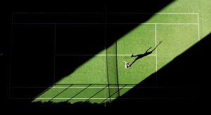 Aerial shot of tennis match from above with player's shadow