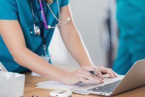Confident nurse uses laptop in doctor's office