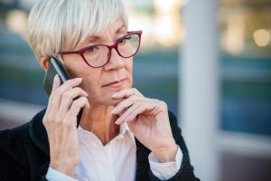 Worried mature businesswoman talking on the mobile phone, resting her arm on chin