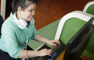 A young visually-impaired woman on an adapted computer, using a screen reader